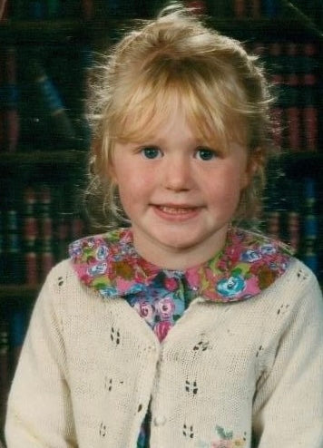 Primary school picture in front of a book backdrop young girl blond hair